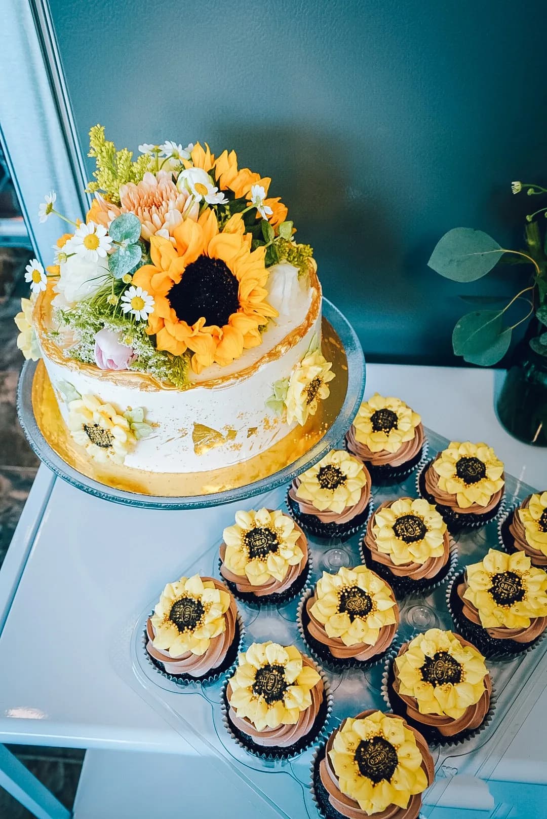 Sunflower cake and cupcakes on a glass stand