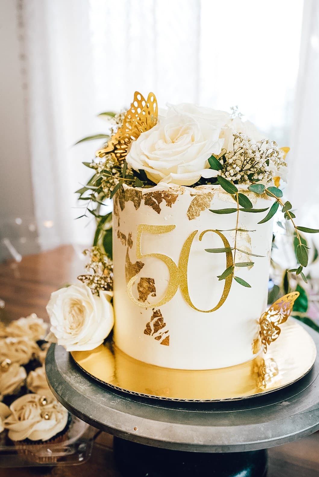 White and gold 50th birthday cake with roses and butterflies