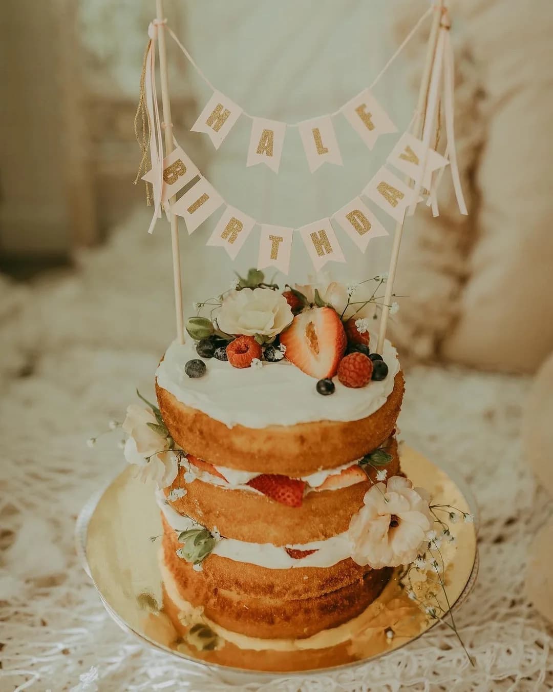 Naked cake with fresh berries and a half birthday banner
