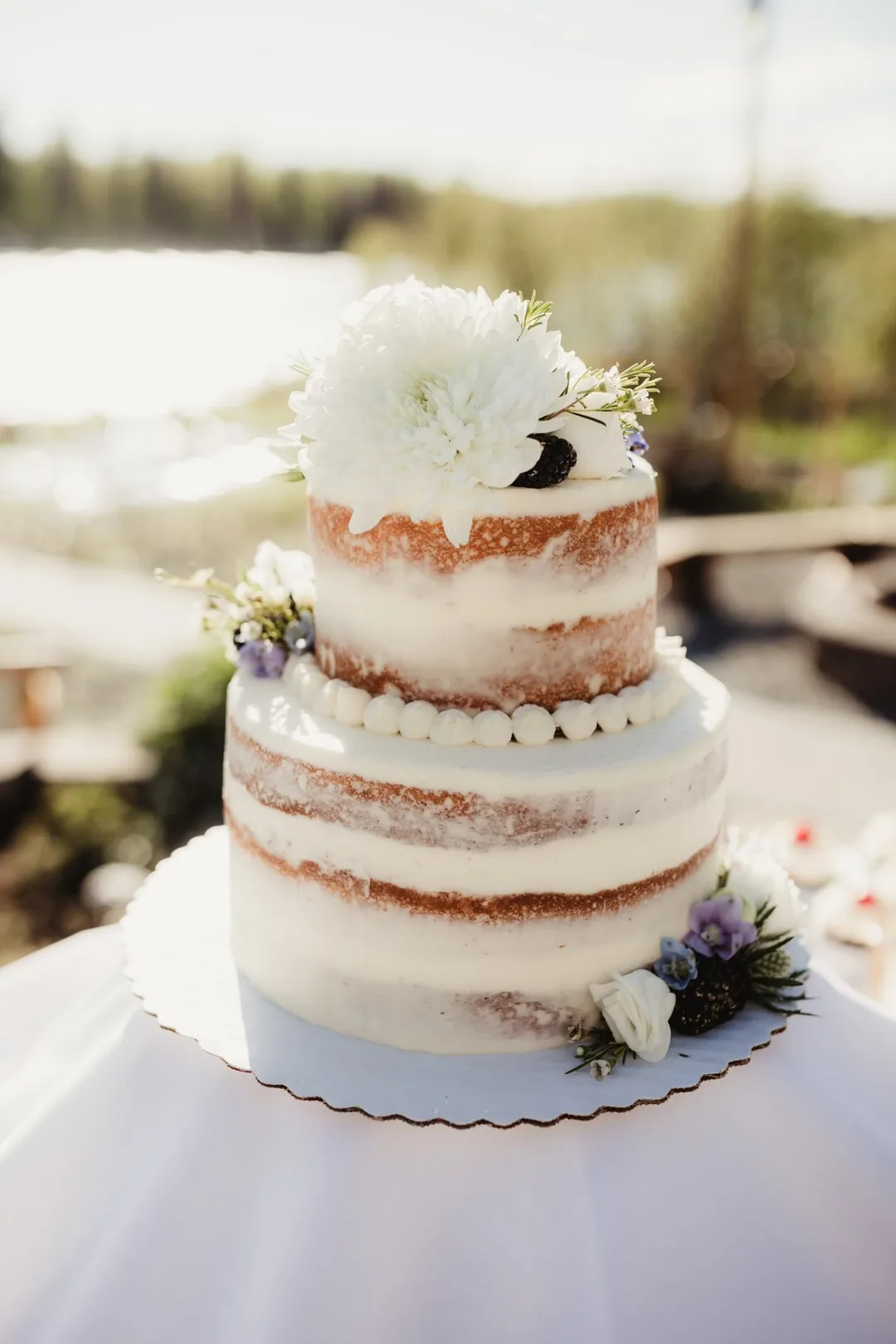 Two-tier naked wedding cake with white dahlia outdoors