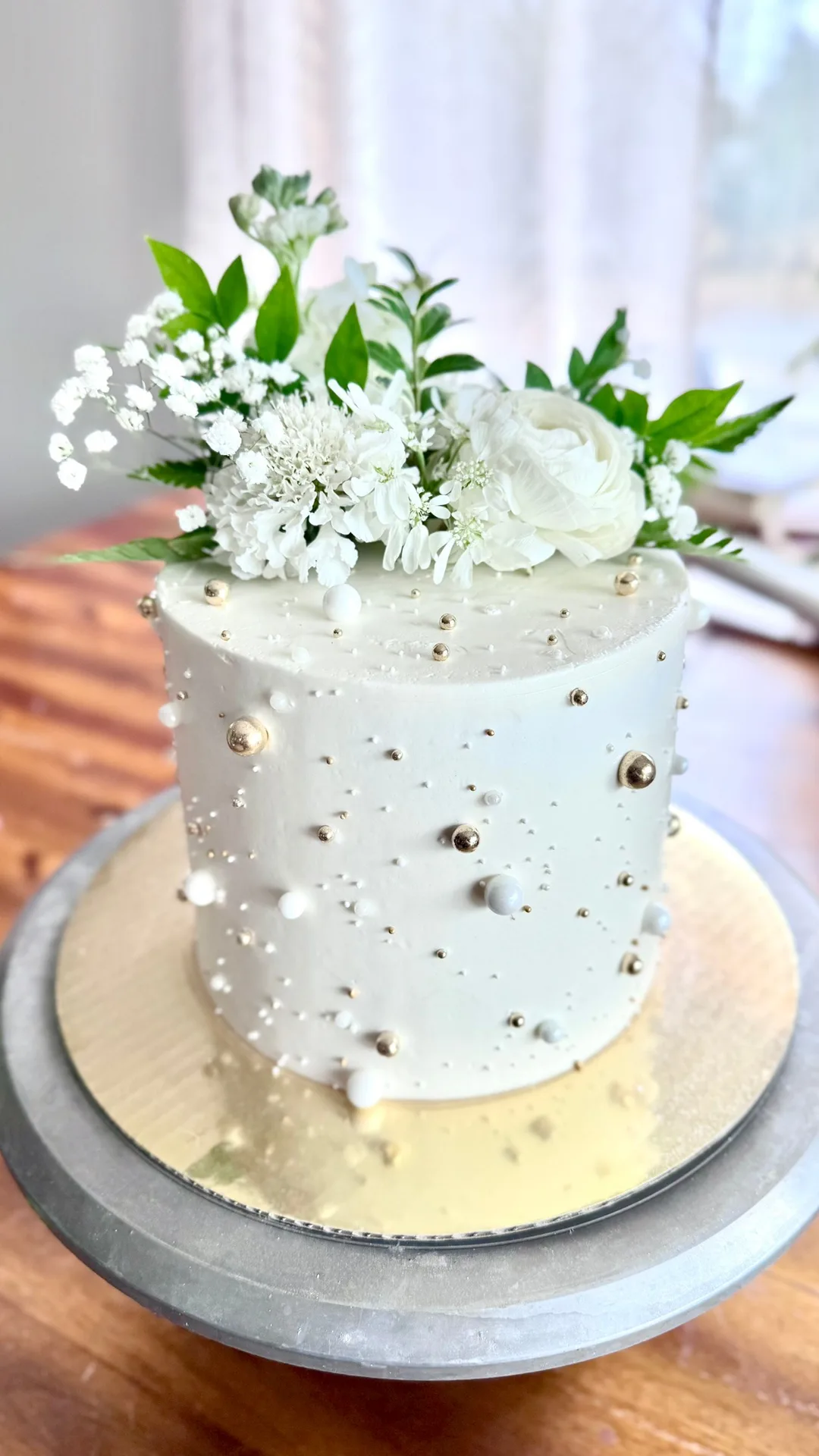 White buttercream wedding cake studded with gold and silver pearls