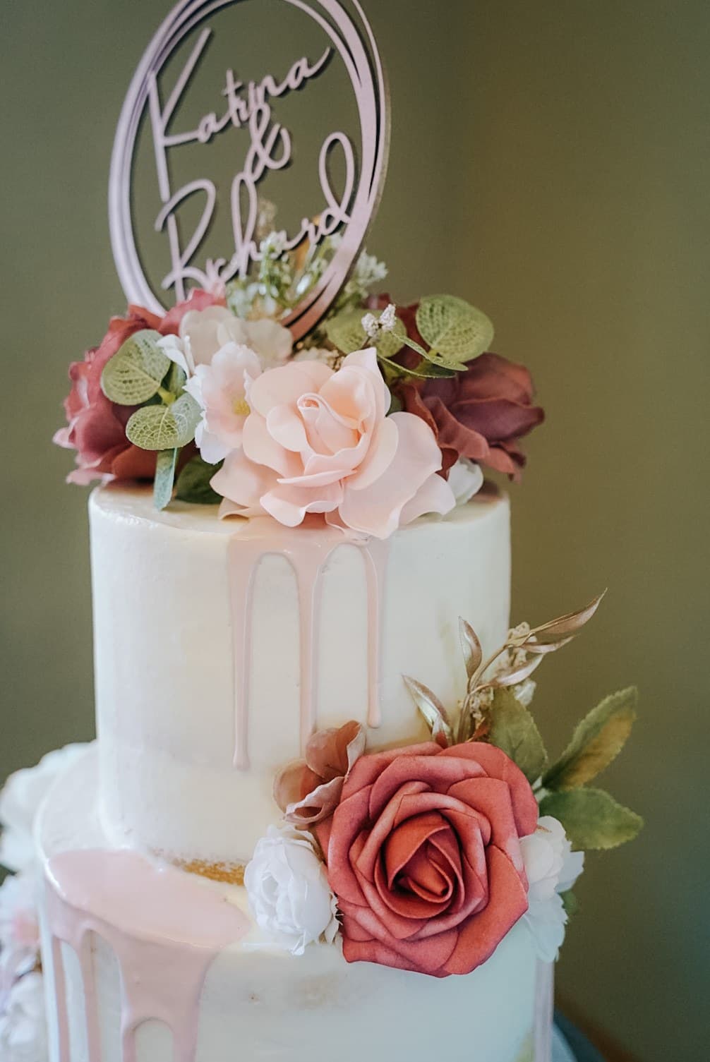 White wedding cake with pink drip and mauve roses