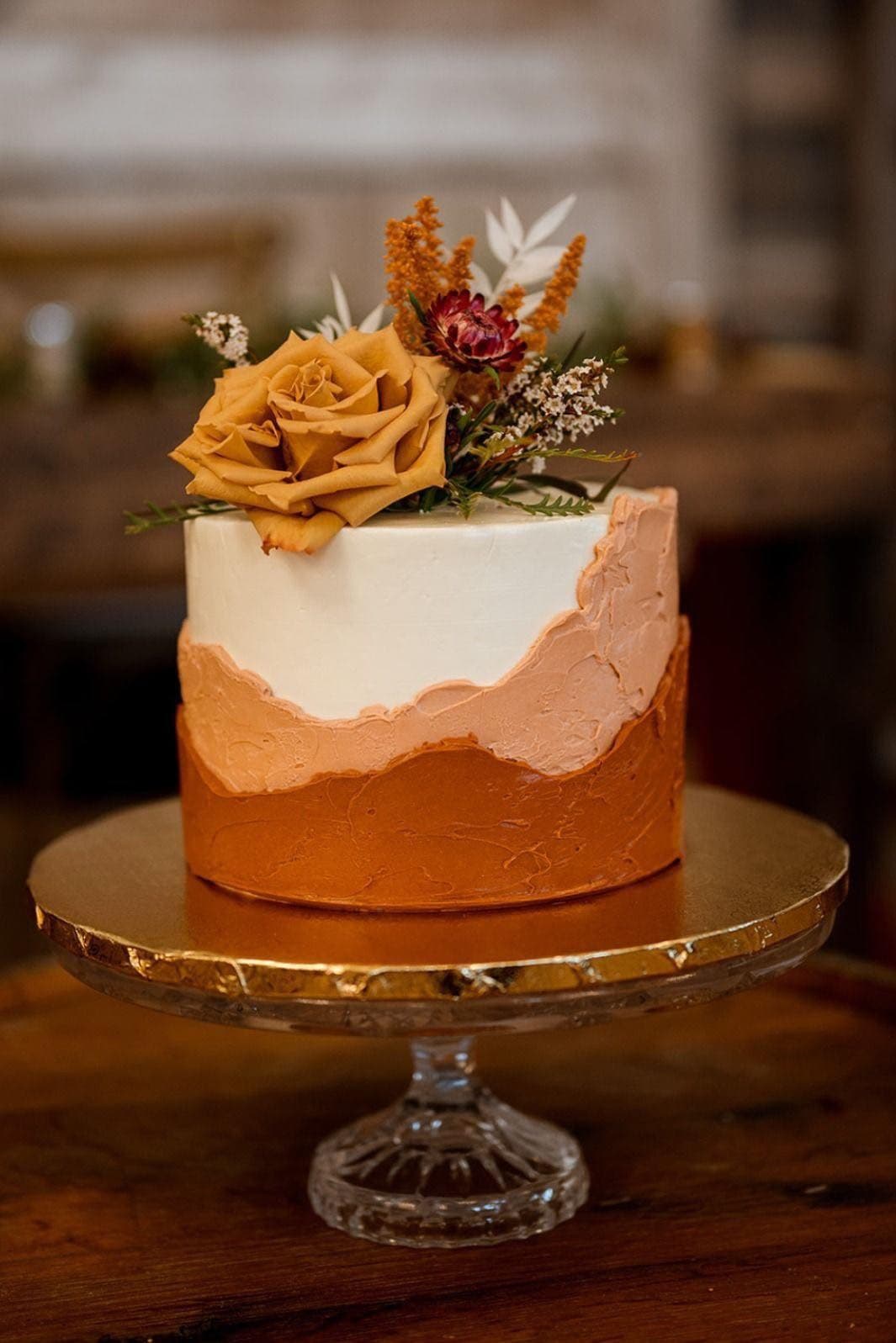 Terracotta and white cake with dried florals and a rust rose
