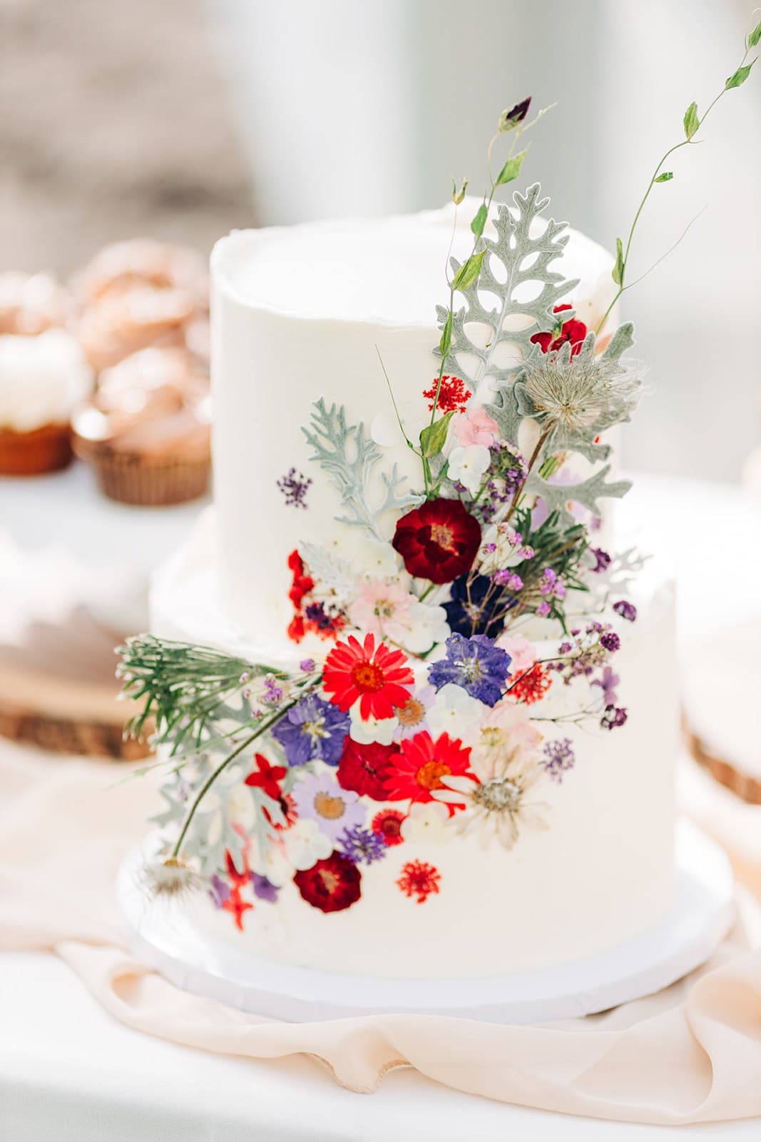 Two-tier white wedding cake with Alaska wildflowers and a dusty miller sprig