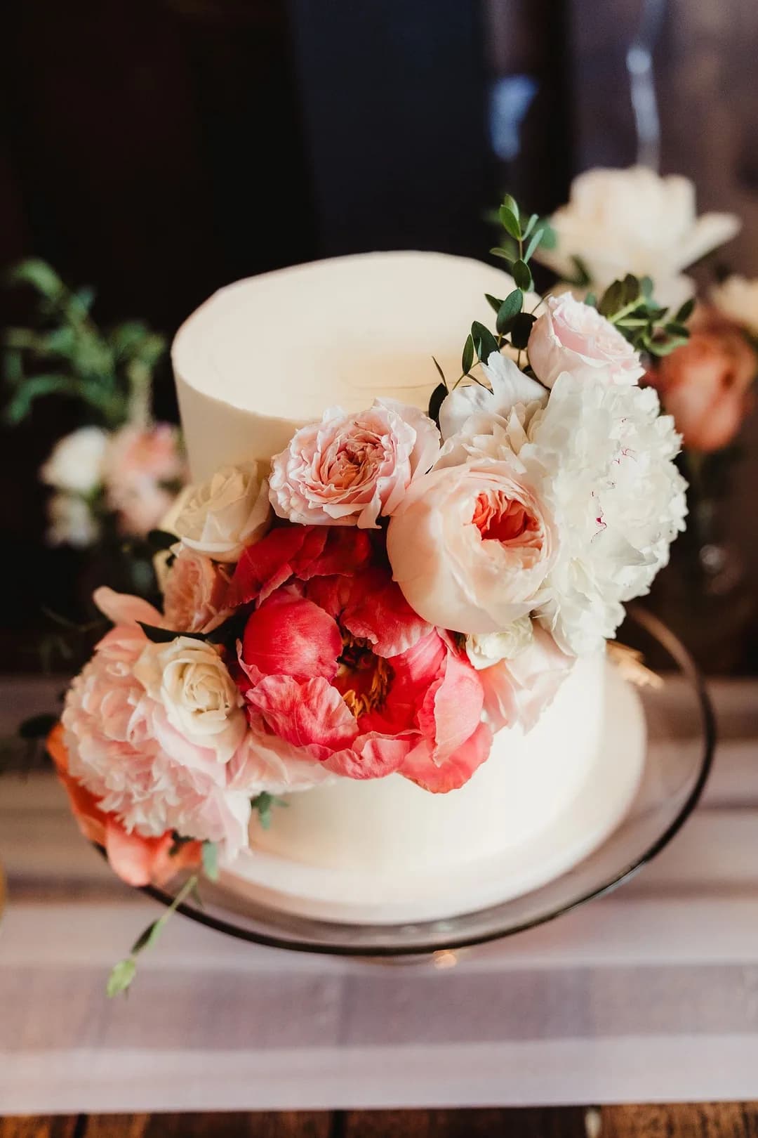 Close-up of blush and coral peonies on a white buttercream wedding cake