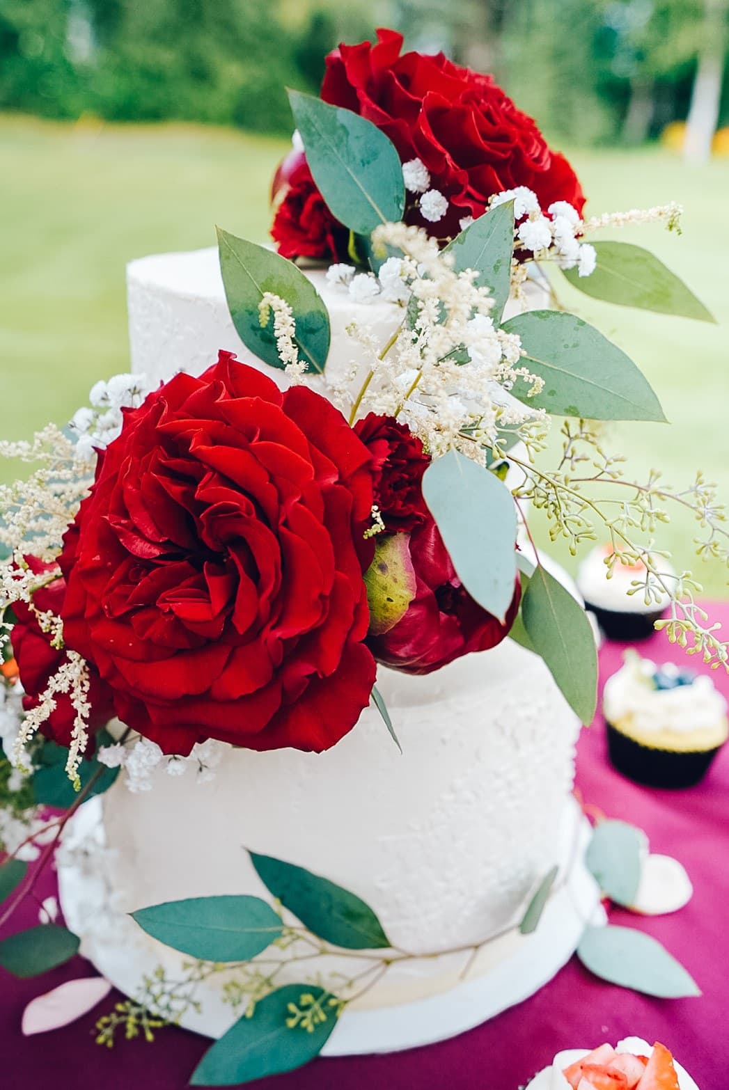 Red garden rose and eucalyptus on a white wedding cake