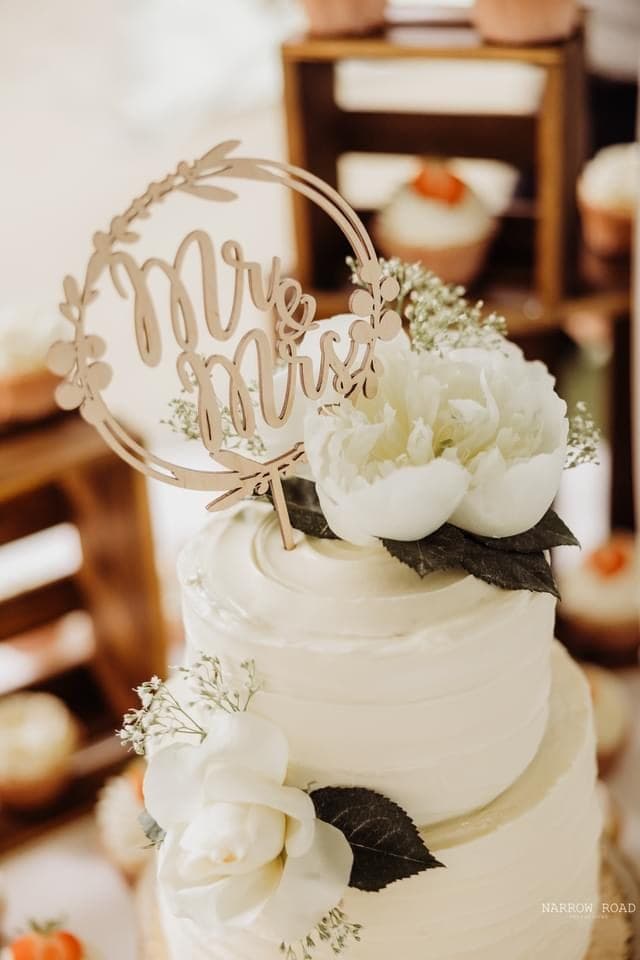 White wedding cake with a peony and wreath topper